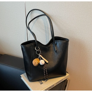 Close-up of black PU leather tote bag featuring a wave-edge design and baseball charm