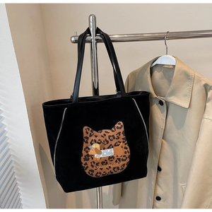 Detail of suede tote bag featuring leopard print cat patch and silver side zipper decoration