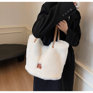 Detailed shot of white faux fur tote bag with brown leather handles and logo patch