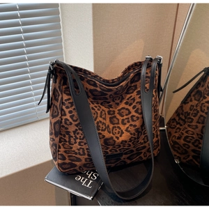 Detail view of leopard print tote bag with black leather straps and side trim details
