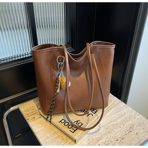 Detail of brown faux leather tote bag with stylish toast pendant and strap on stone surface