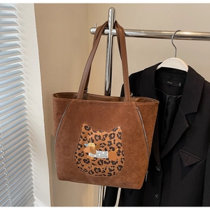 Detail of coffee brown tote featuring leopard cat patch and embroidered dachshund dog