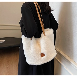 Detailed side view of a large white plush tote bag with brown leather shoulder straps