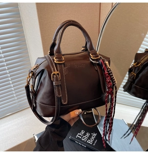 Dettaglio borsa vintage marrone scuro con finiture dorate e ciondolo a nappa intrecciata