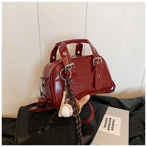 Detail of red patent leather pillow bag with baseball keychain and metal buckle hardware