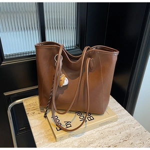 Detailed view of a brown leather tote bag with a spherical charm on a marble surface