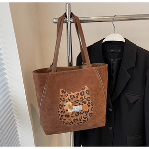 Detail of dark brown suede tote bag with leopard print dog patch and silver zipper