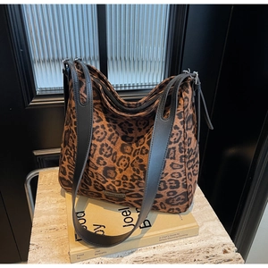 Detail view of leopard print tote bag texture with leather strap and metal buckle