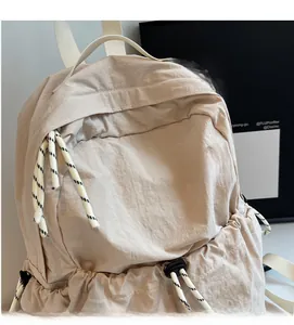 Détail du sac à dos en nylon beige montrant le tissu doux et les tirettes rayées