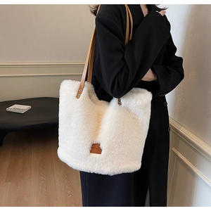 Detail of plush cream faux fur tote bag with brown leather straps and rivet accents