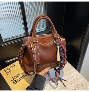 Dettaglio della borsa Boston vintage marrone con foulard in seta e ciondolo in legno