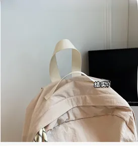 Détail de la poignée en nylon renforcé et des coutures sur le sac à dos de voyage beige