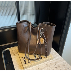 Detail of dark brown leather tote bag with creative baseball charm and brand logo