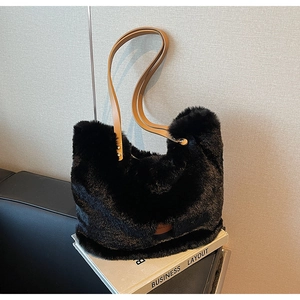 Close-up of black faux fur tote bag with brown leather handles and circular logo patch