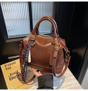 Dettaglio borsa a bauletto marrone vintage con cuciture bianche e nappa decorativa