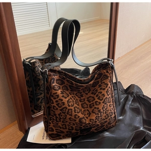 Close-up of leopard print tote bag fabric with black leather straps on silk background