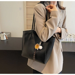Close-up of black matte tote bag with creative mini baseball glove and ball pendant