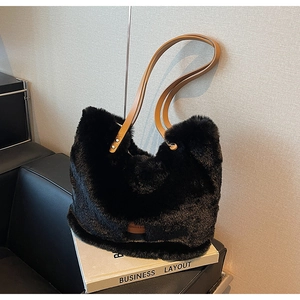 Detail of black faux fur tote bag with brown leather straps and metal rivets on display
