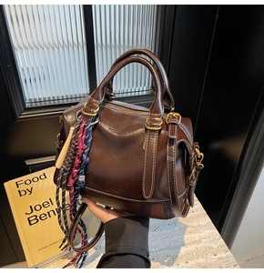 Dettaglio della borsa Boston in pelle marrone scuro con ciondolo in corda intrecciata