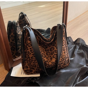 Detail of hobo tote bag featuring leopard print fabric and black leather strap