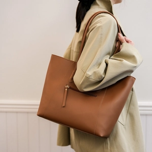 Close-up of brown faux leather tote bag with side zipper pocket and stitching details