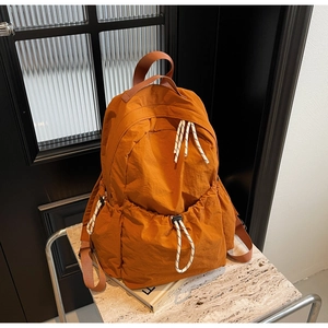 Détail du sac à dos en nylon orange avec poche à cordon et texture plissée moderne