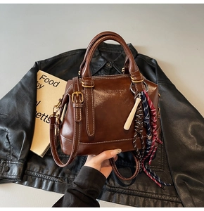 Dettaglio della borsa Boston vintage marrone con ciondolo intrecciato tricolore