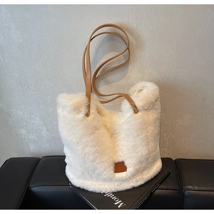 Detail of white faux fur tote bag with brown leather straps and metal rivets