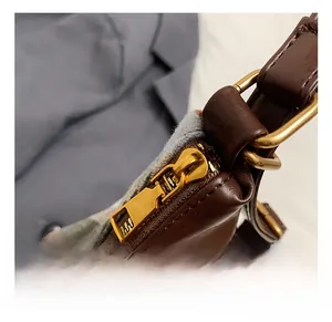 Détail de la fermeture éclair dorée et de la boucle sur un sac en cuir marron