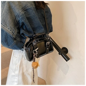 Detail of black patent leather Boston bag with silver buckle and cute animal charm