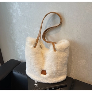 Detail of white faux fur tote bag with brown leather tag on a stylish magazine
