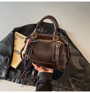 Dettaglio borsa Boston in pelle lucida marrone con cuciture a contrasto e foulard di seta