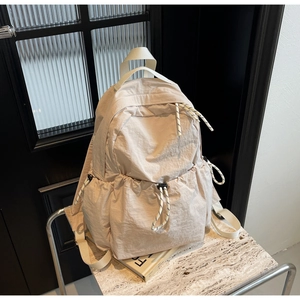 Détail d'un sac à dos en nylon crème avec poches latérales à cordon de serrage réglable