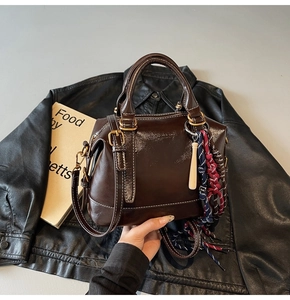 Dettaglio borsa Boston marrone scuro lucido con cuciture bianche e finiture oro