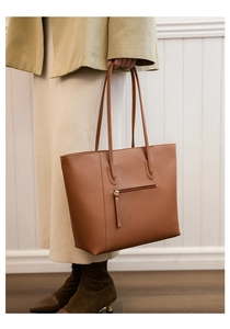 Detailed view of large brown leather tote bag back zipper pocket and slim shoulder straps