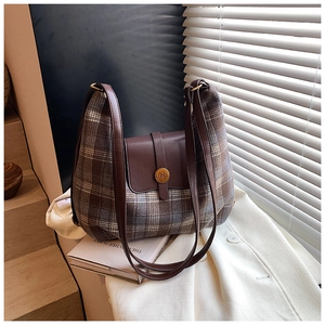 Détail d'un sac à bandoulière vintage à carreaux sur blazer blanc et livres éclairés