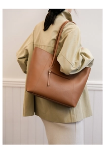 Detail view of large dark brown leather tote bag showing back zipper pocket and shoulder strap