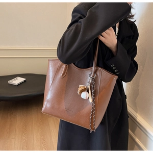 Macro view of brown large capacity tote bag with embossed logo and sports charm detail