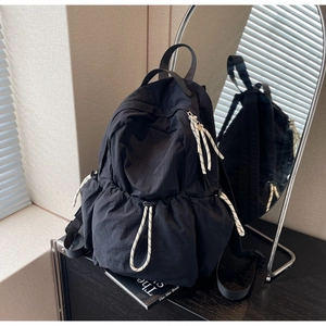 Vue détaillée du sac à dos de voyage en nylon noir avec poche à cordon sur bois