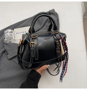 Dettaglio della borsa a mano nera in pelle con corda intrecciata e tracolla rimovibile