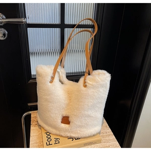 Detail of white faux fur tote bag with brown leather straps on marble surface