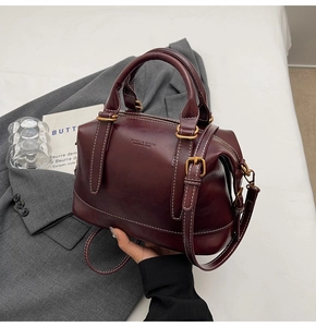 Dettaglio della borsa Boston bordeaux con logo in rilievo e hardware dorato vintage