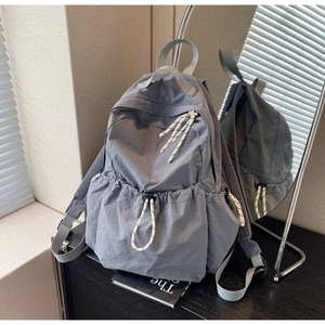 Détail du sac à dos de voyage en nylon gris avec poches à cordon et reflet latéral du miroir