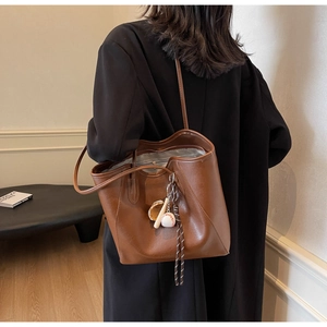 Brown faux leather tote bag detail with baseball charm and spacious zipper interior compartment