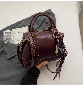 Dettaglio borsa Boston vintage bordeaux con cuciture bianche e ciondolo a nappe