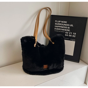 Detail of soft black faux fur tote bag with brown leather straps on marble surface