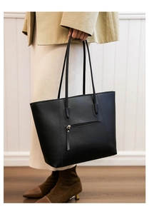 Detail of minimalist black leather tote bag featuring a practical back zipper pocket