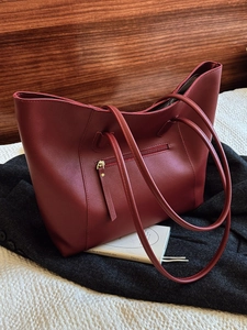 Retro burgundy large capacity tote bag in faux leather with shoulder straps on a grey coat