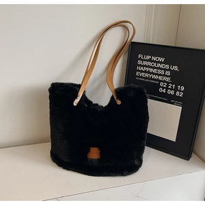 Close-up of black fuzzy tote bag with brown faux leather straps and metal rivets