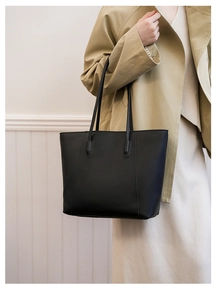 Fashionable large black matte leather tote bag shown on model in a casual city outfit